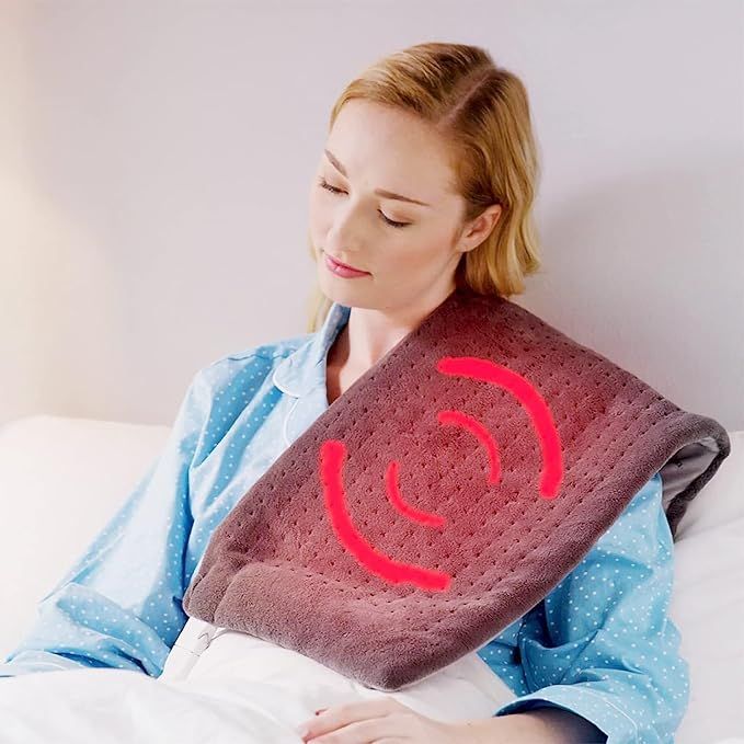 Woman using a heating pad on her shoulder with a red heat symbol.