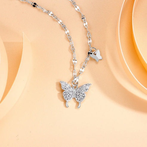 Silver butterfly necklace on a beige background