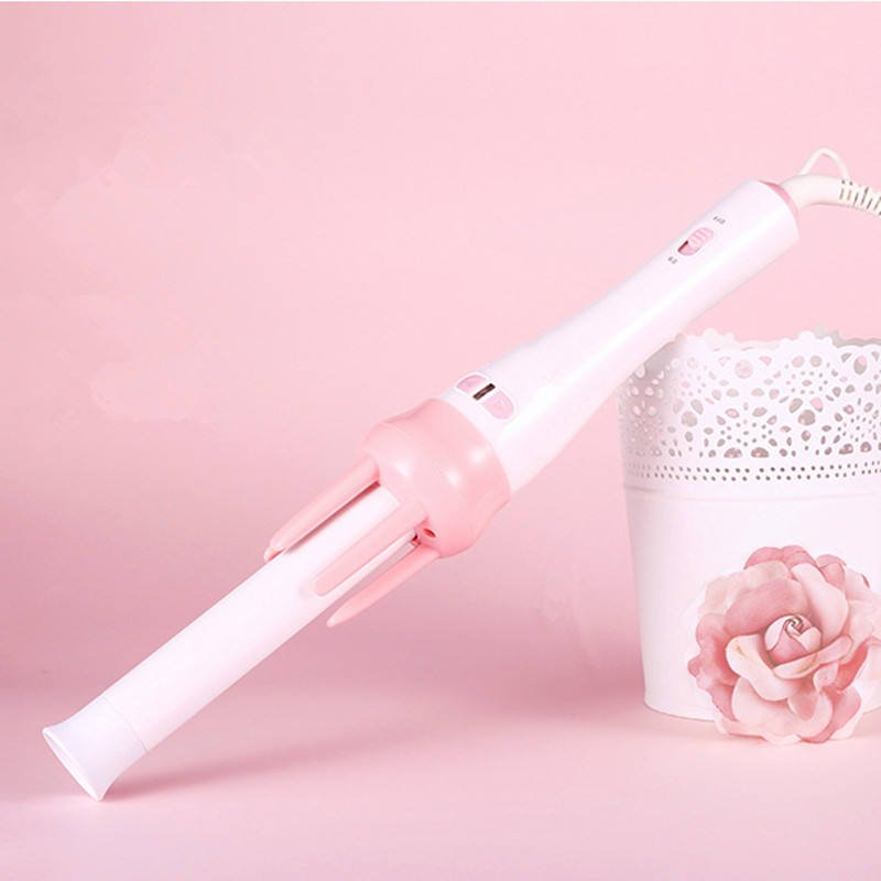 Pink and white hair curler on a pink background with a decorative basket and rose. hair beauty comb brush